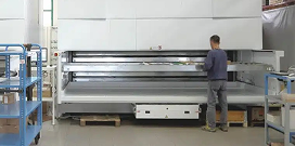 Worker operating an automated vertical lift storage system in a warehouse environment.