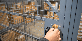 A worker uses a key to lock a protective metal cage to keep inventory safe