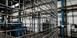 Close-up of industrial wire mesh fencing inside a warehouse or manufacturing facility.