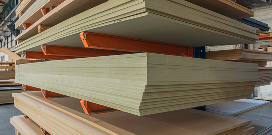 An orange medium-duty cantilever rack holding piles of lumber in a warehouse facility