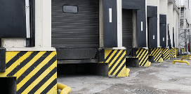 Warehouse loading dock bays with roll-up doors and black-and-yellow safety bumpers.