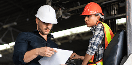 Two hard-hat workers look over a document together.