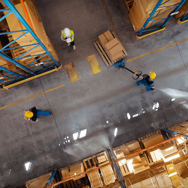 Overhead view of workers using pallet jack to move packages in a warehouse