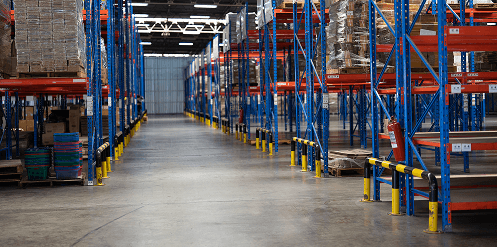 A worker uses a forklift to carry pallets with packages in a large warehouse