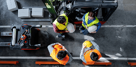 A worker uses a forklift to carry pallets with packages in a large warehouse