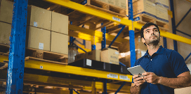A worker uses a forklift to carry pallets with packages in a large warehouse